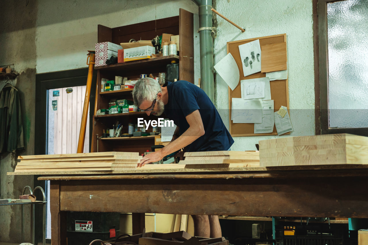 Craftsman working on wooden planks in workshop