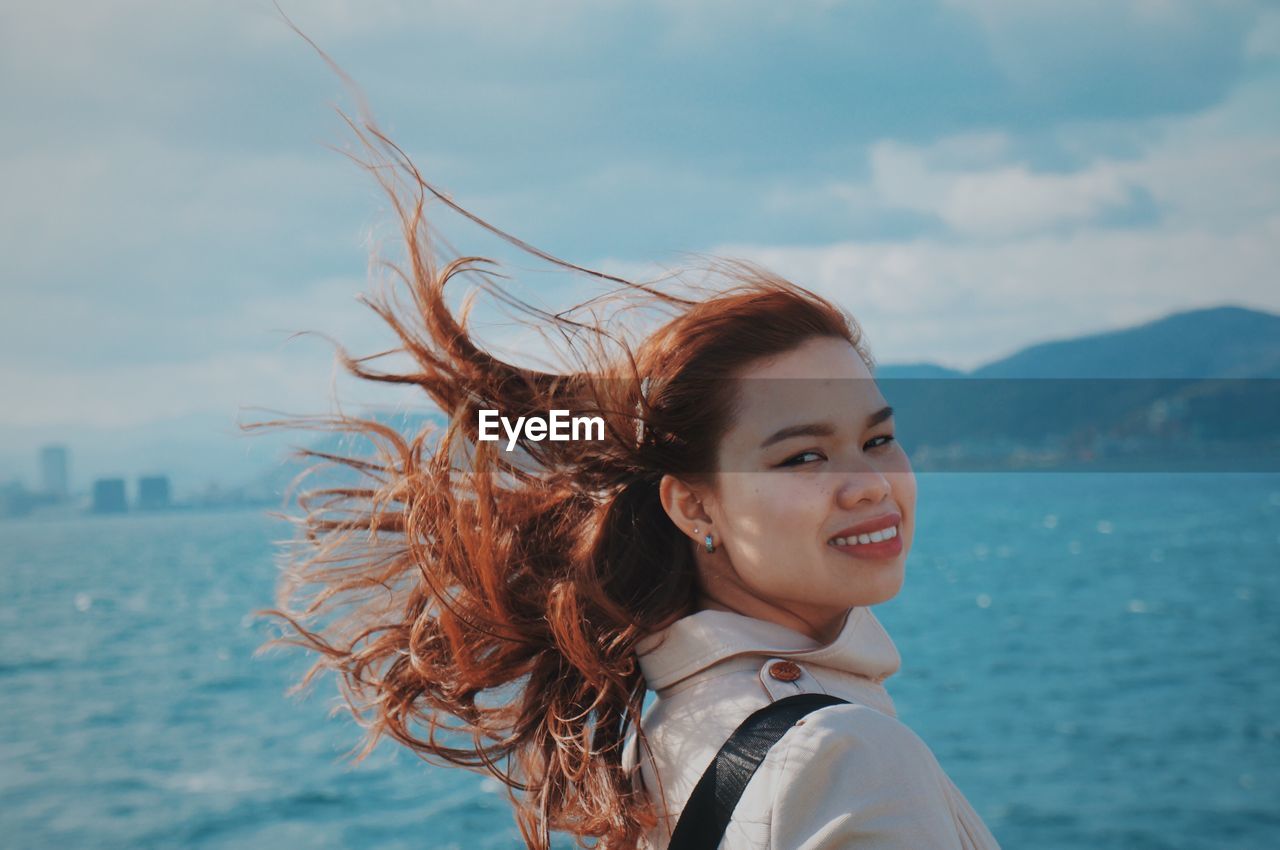 Portrait of happy woman against sea against sky