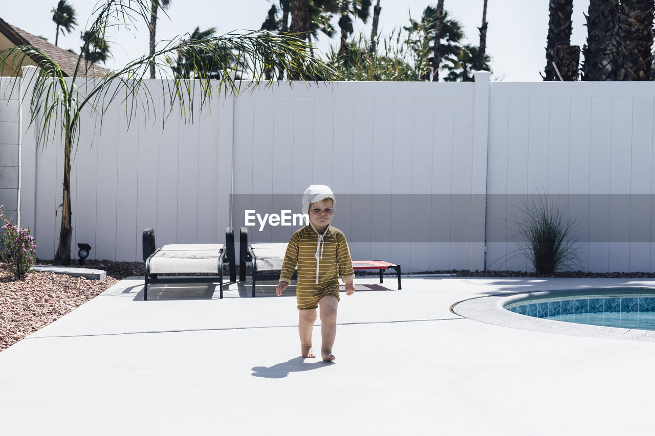 Boy walking at patio on sunny day