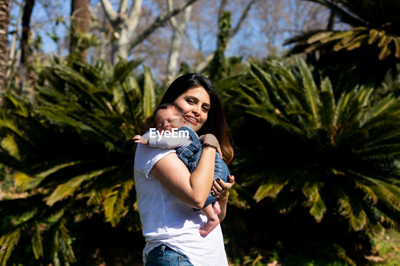 portrait of smiling young woman standing against trees