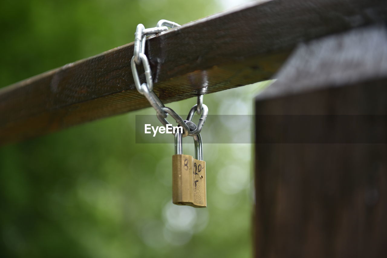 Close-up of padlock hanging to chain on railing