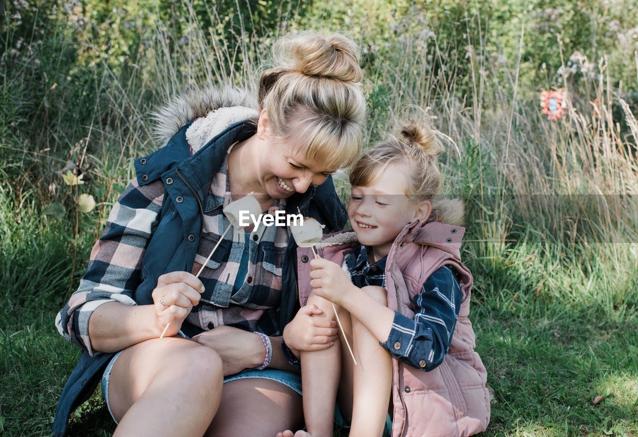 Mother and daughter toasting marshmallows together smiling happily