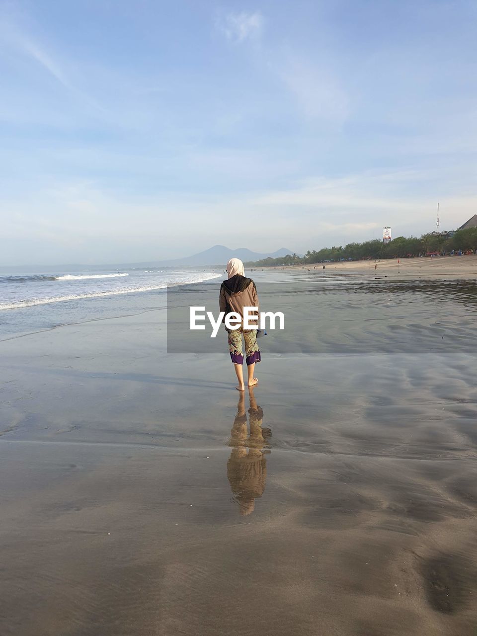 Rear view of woman on beach against sky