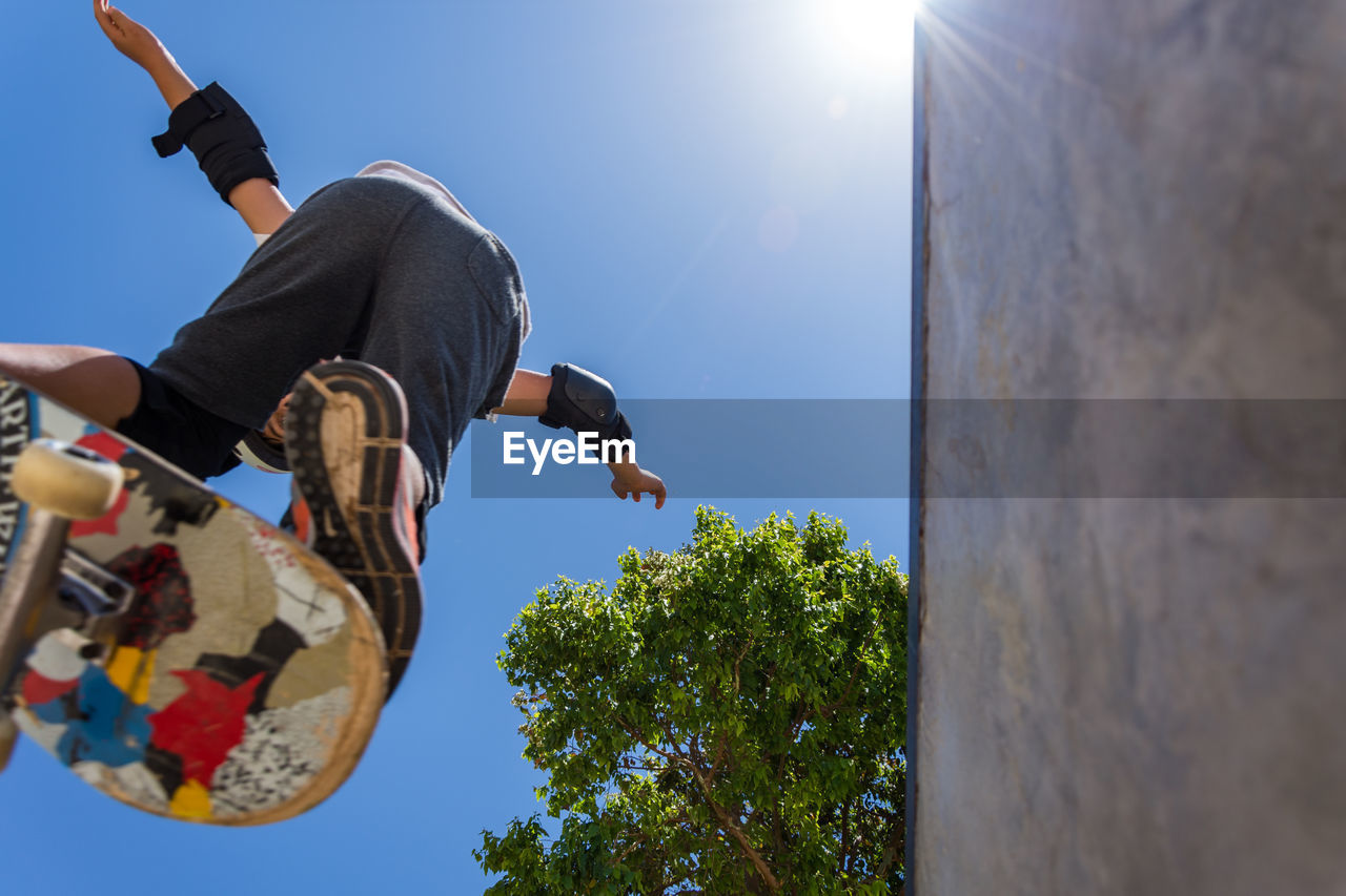 Low angle view of man performing stunt while skateboarding against sky