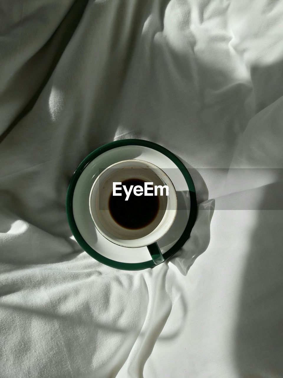 Directly above view of black coffee in cup on bed