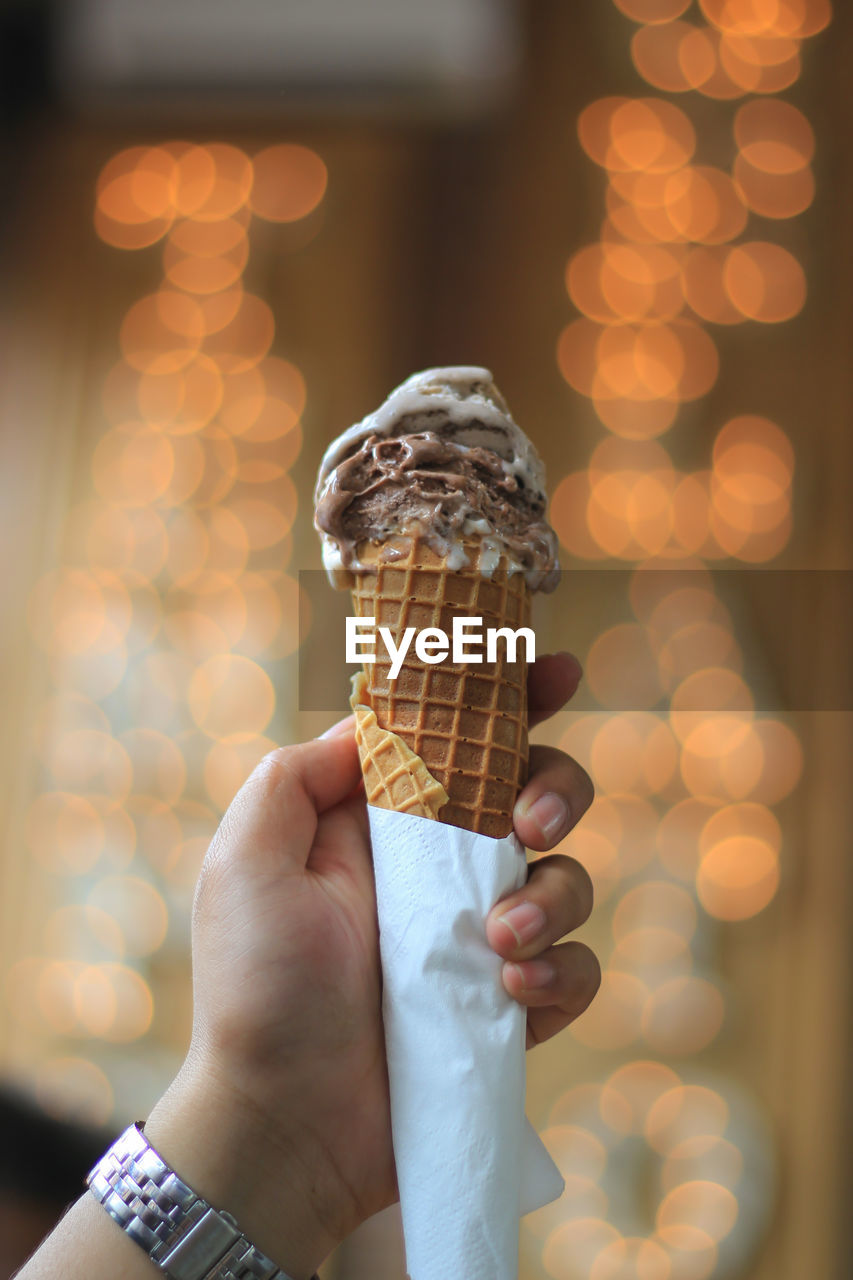 Close-up of hand holding a chocolate and vanilla ice cream in cone 
