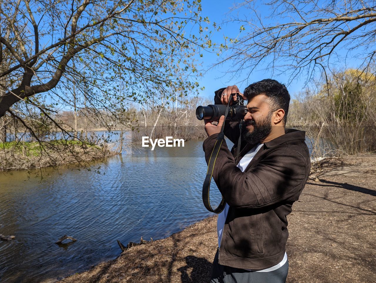 Side view of men photographing through camera against sky