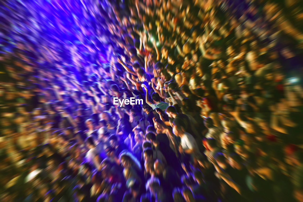 Zoom in effect on a blurred crowd partying at a music festival