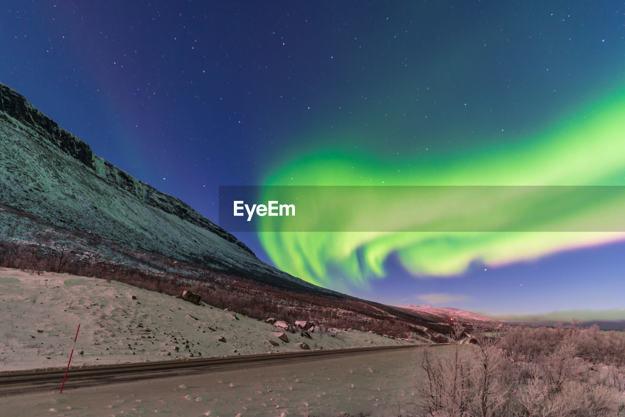 Scenic view of road against sky at night with northern lights