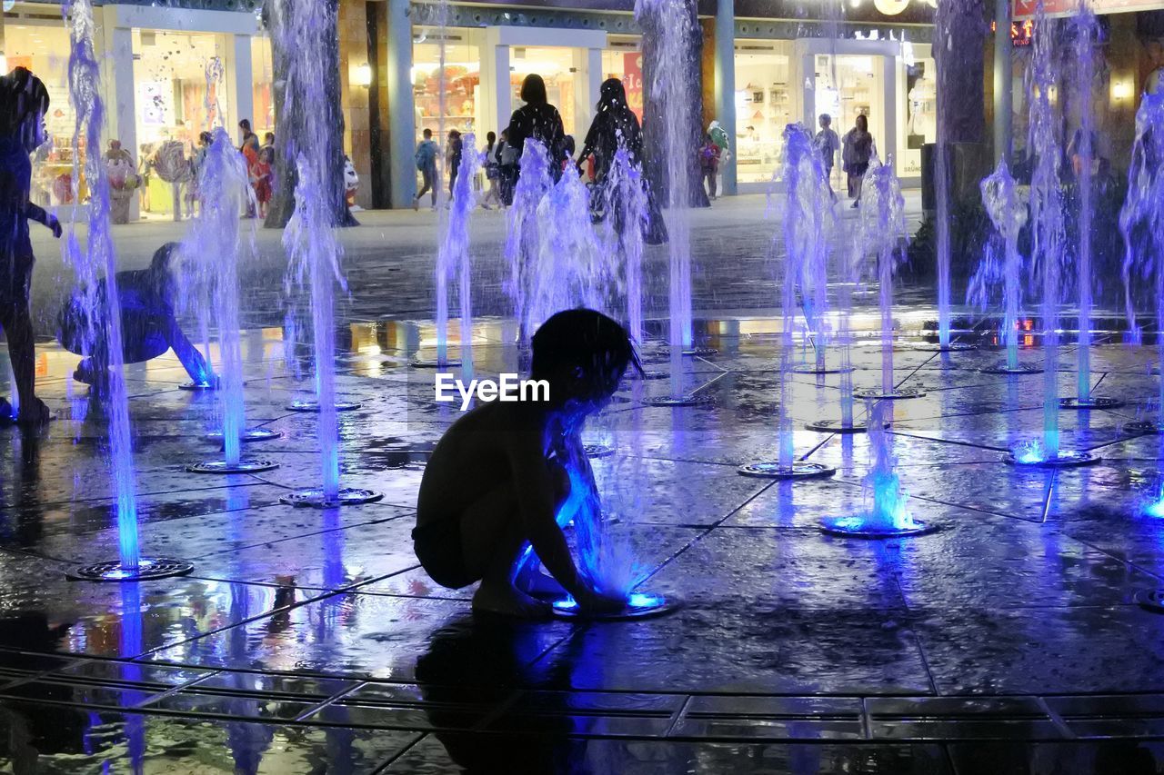 REAR VIEW OF SILHOUETTE PEOPLE AT ILLUMINATED WATER