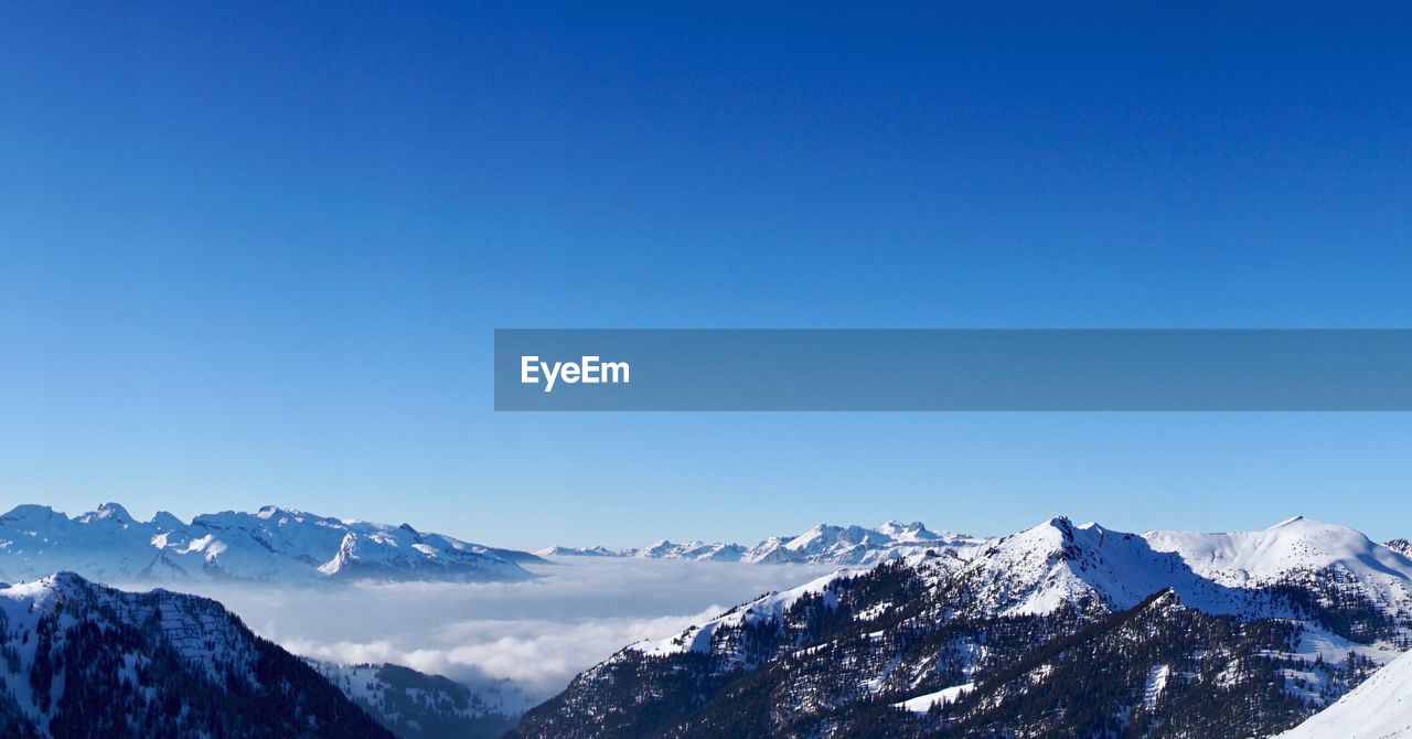 Scenic view of snowcapped mountains against clear blue sky