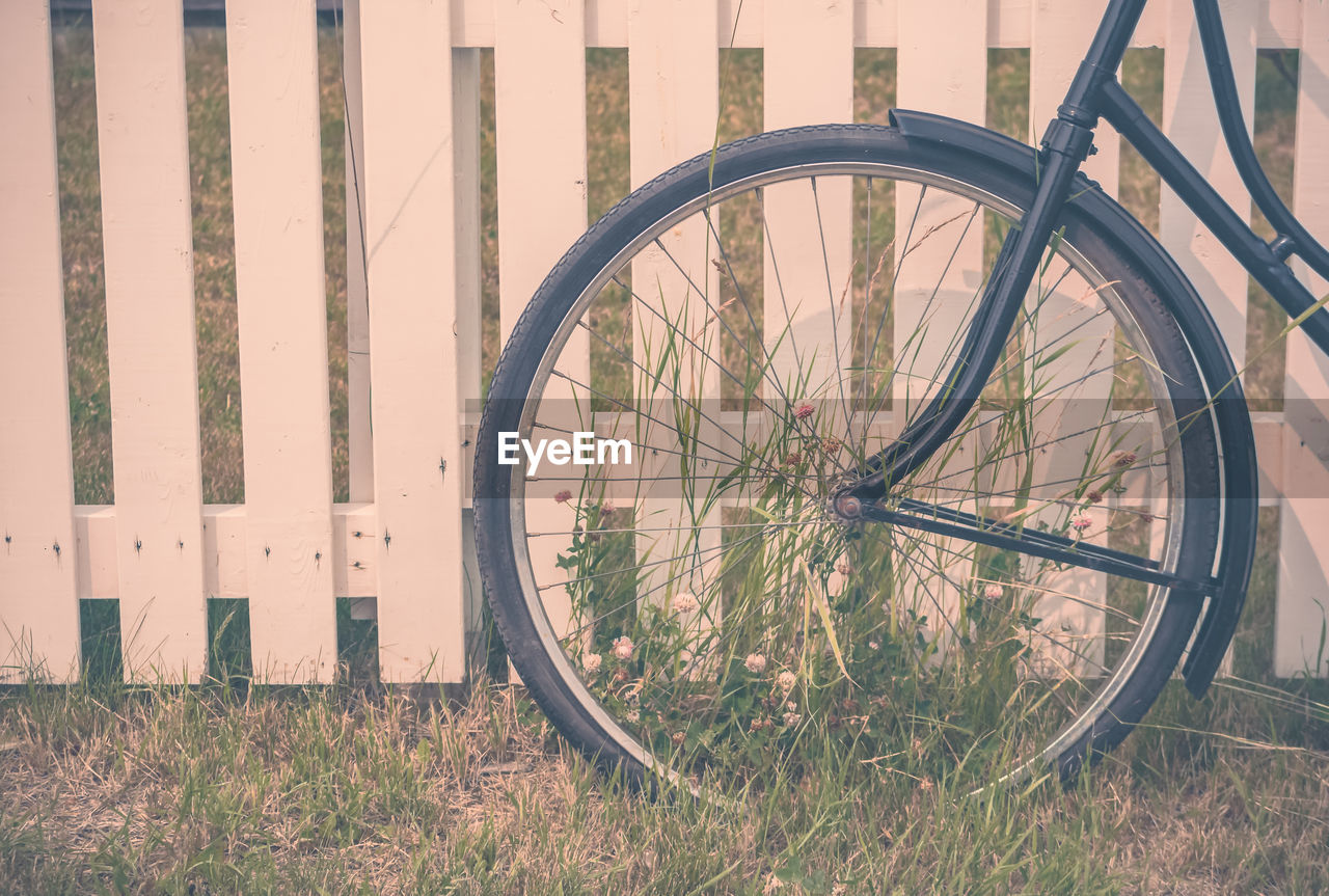 Cropped image of bicycle parked by fence in yard