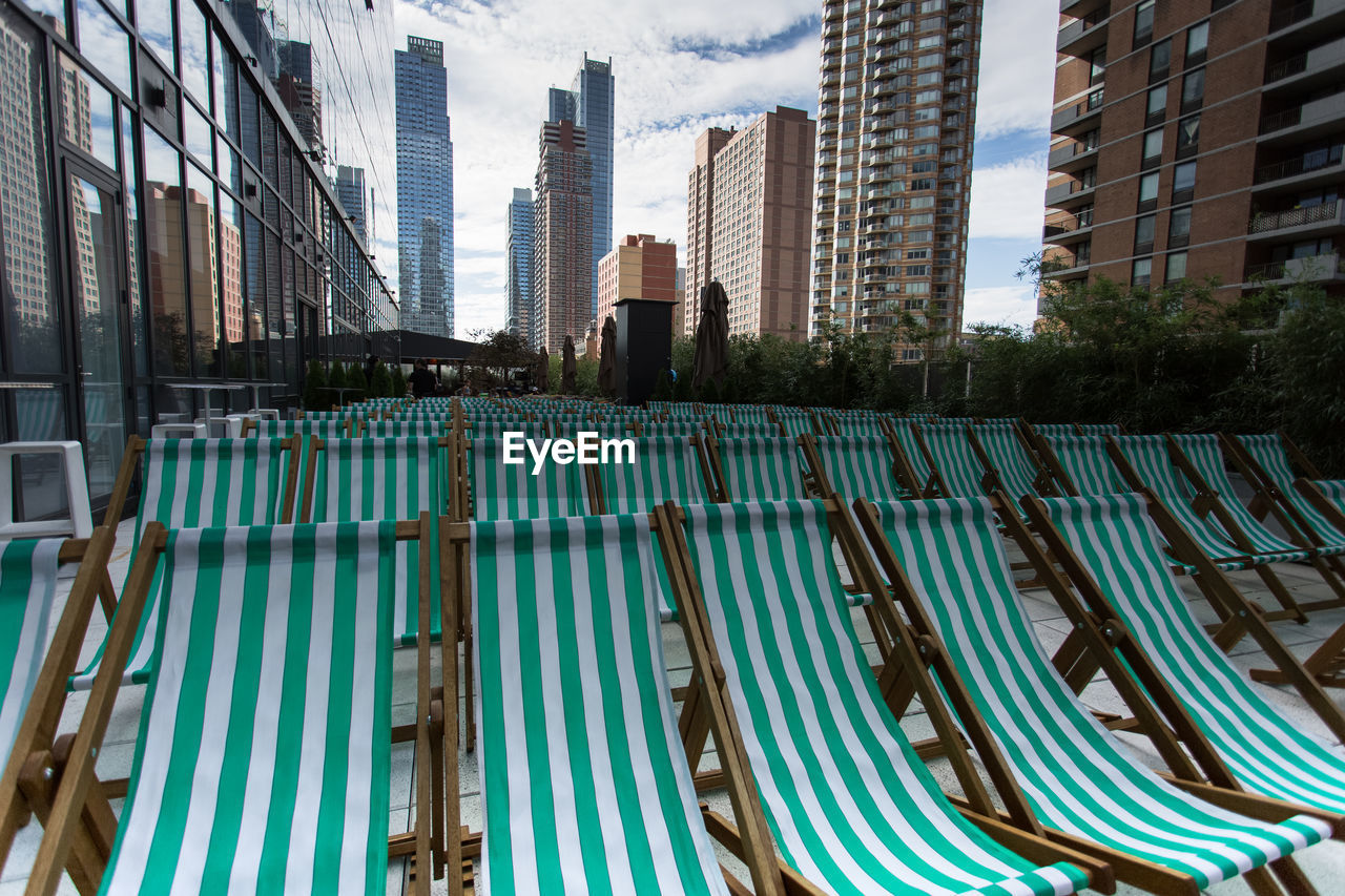 Green deck chairs amidst modern buildings in city