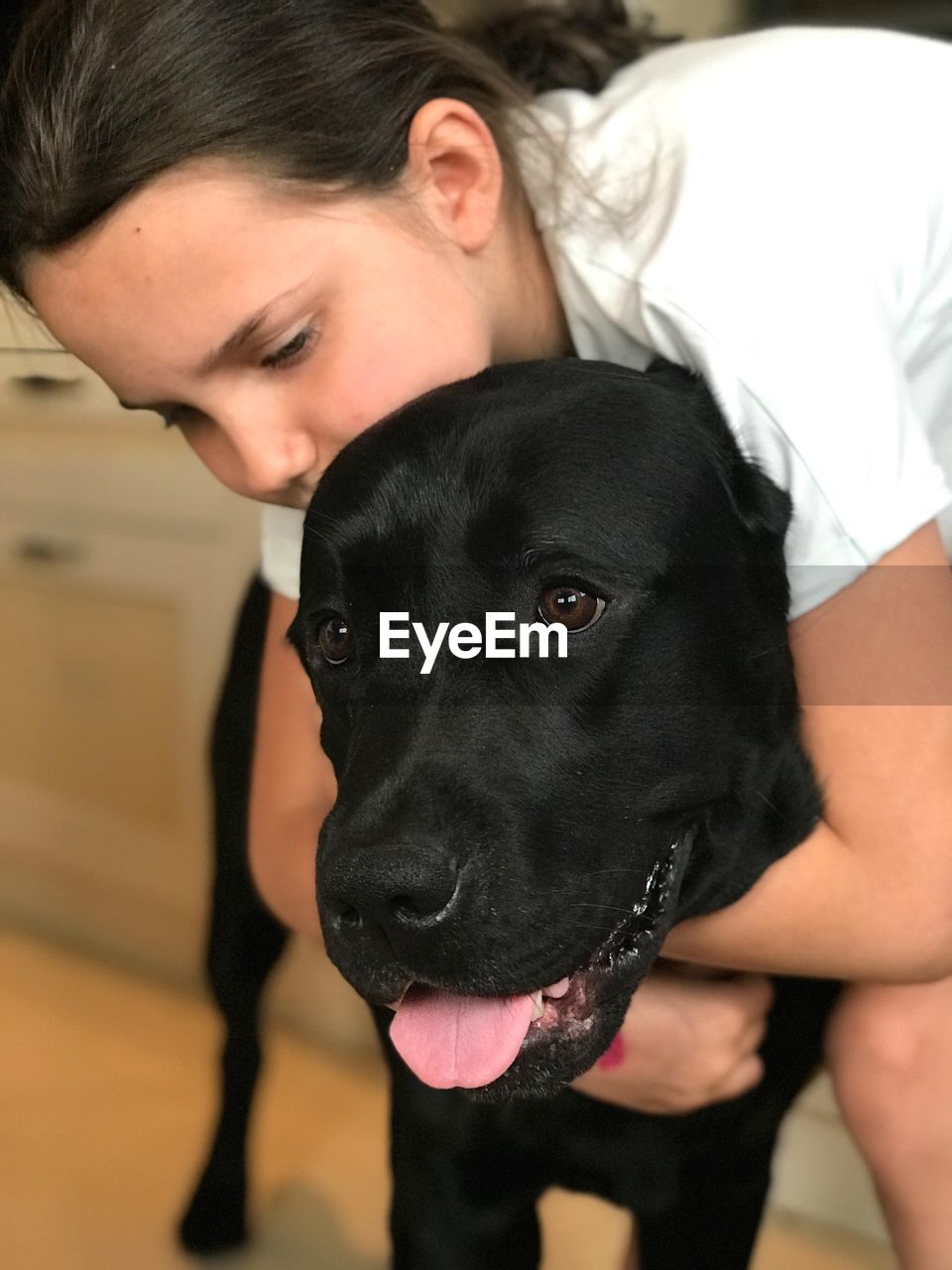 Girl embracing black dog at home