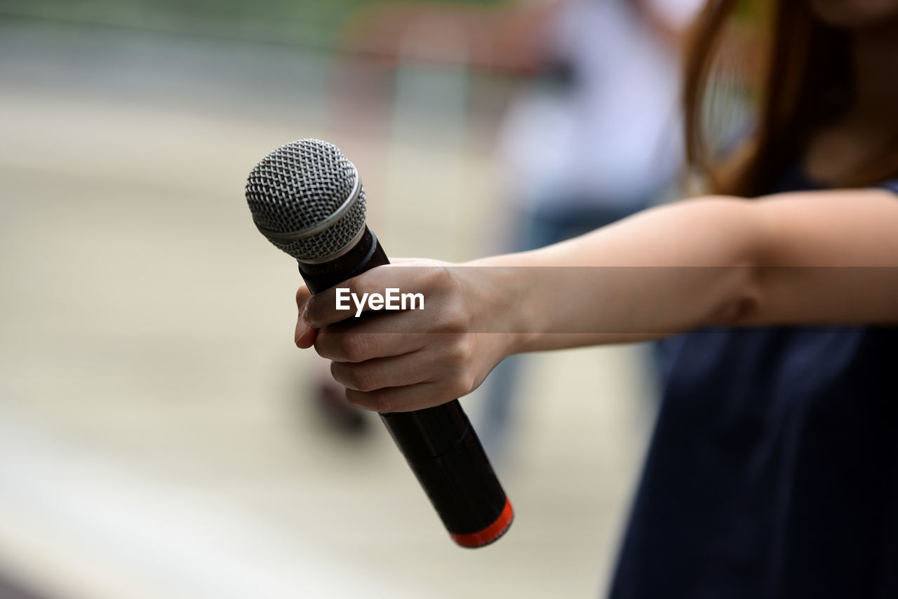 Midsection of woman holding microphone