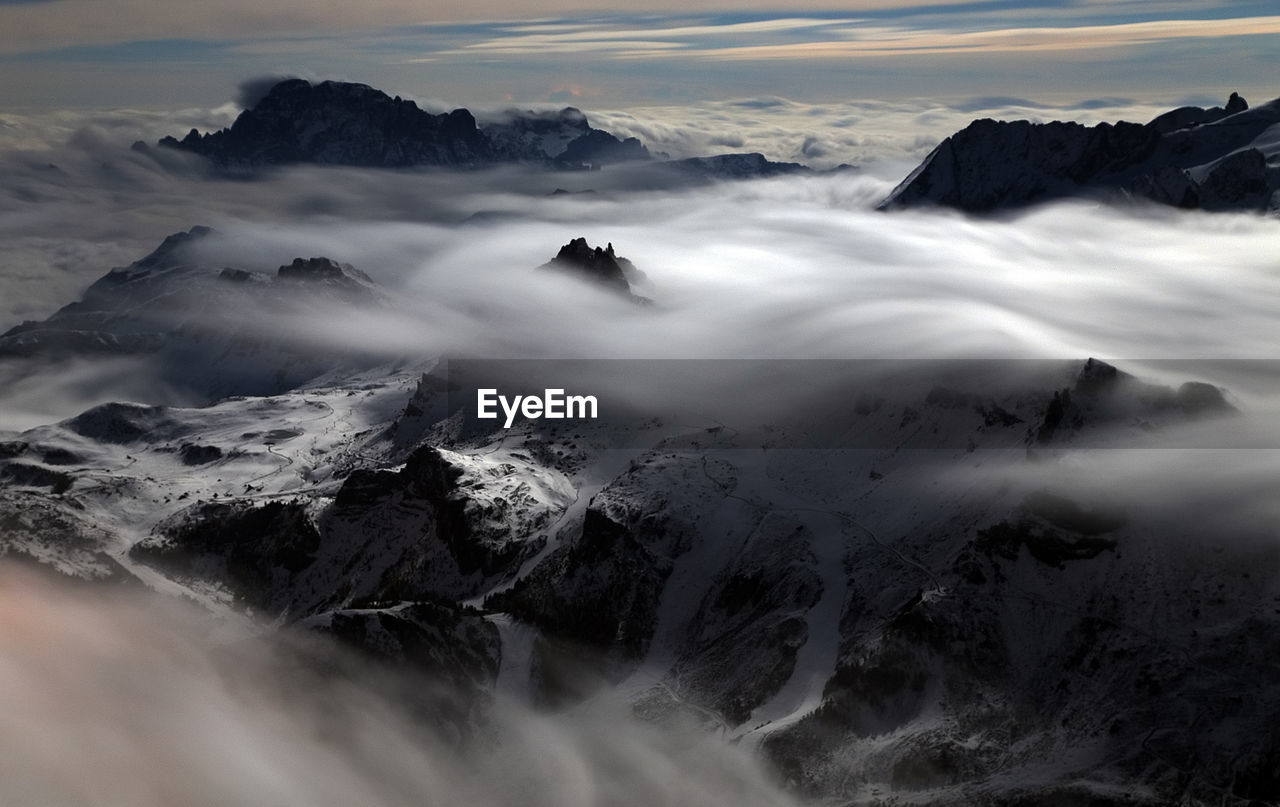 Scenic view of clouds covering snowcapped mountains