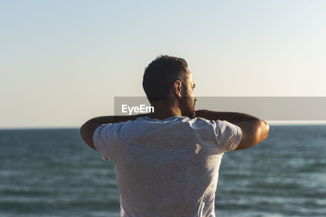 Rear view of man looking at sea against sky