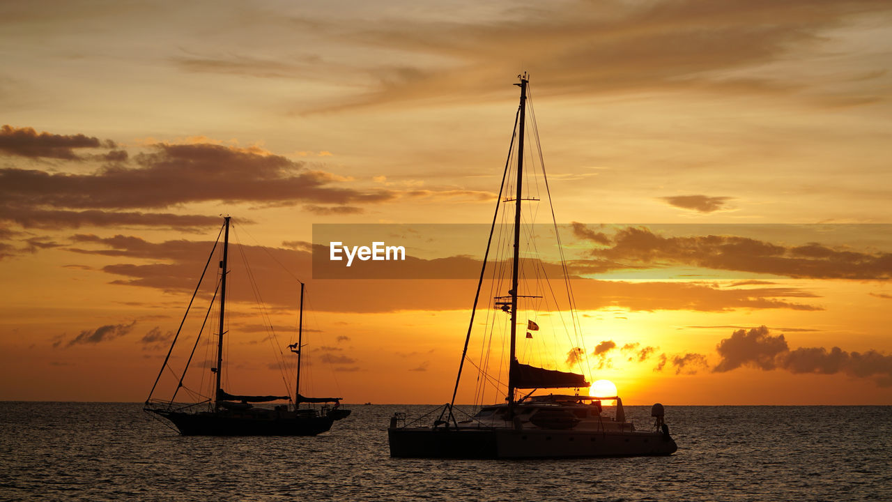 SILHOUETTE SAILBOAT IN SEA AGAINST SKY DURING SUNSET