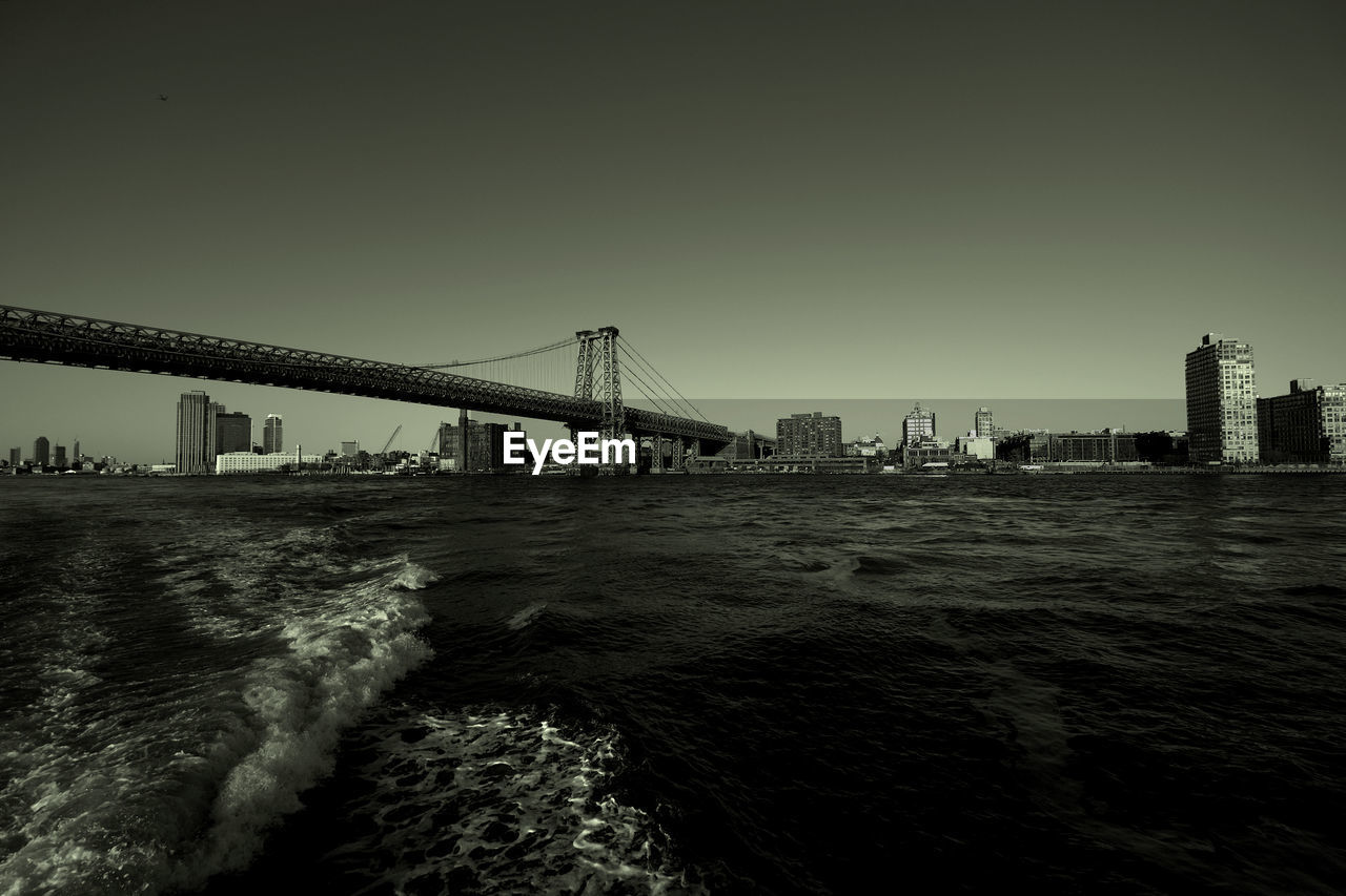 BRIDGE OVER CITY BY SEA AGAINST CLEAR SKY