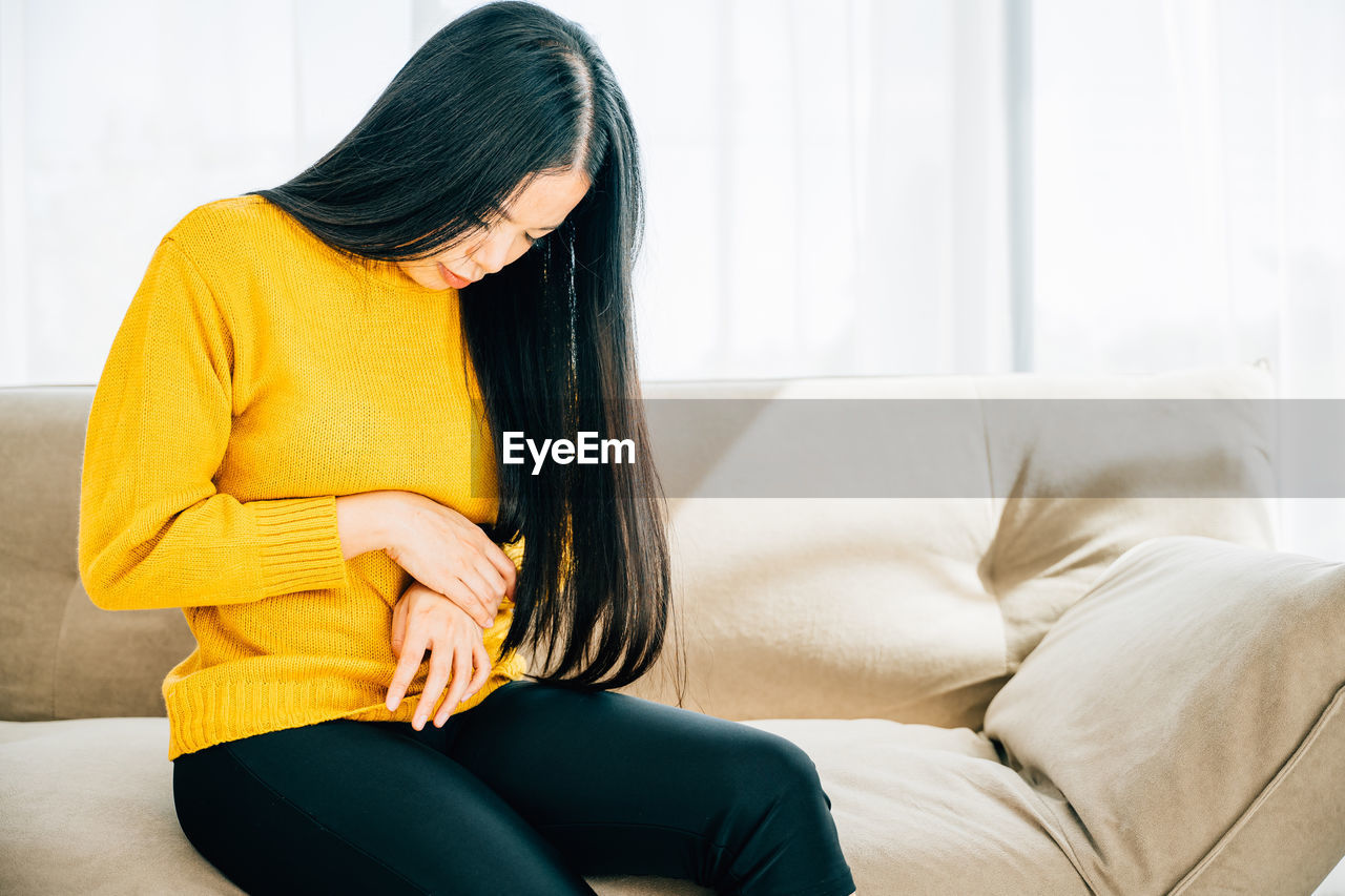 low section of woman sitting on sofa at home