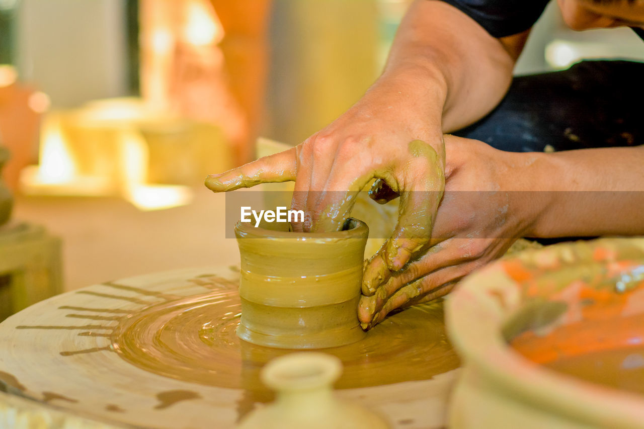 cropped hands of man making pot