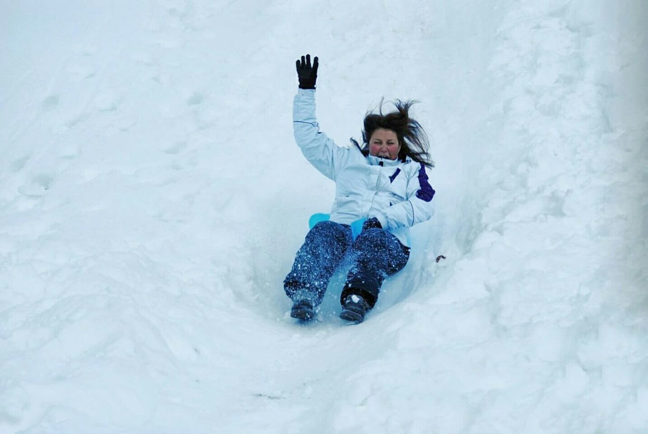 High angle view of woman sliding on snow covered hill