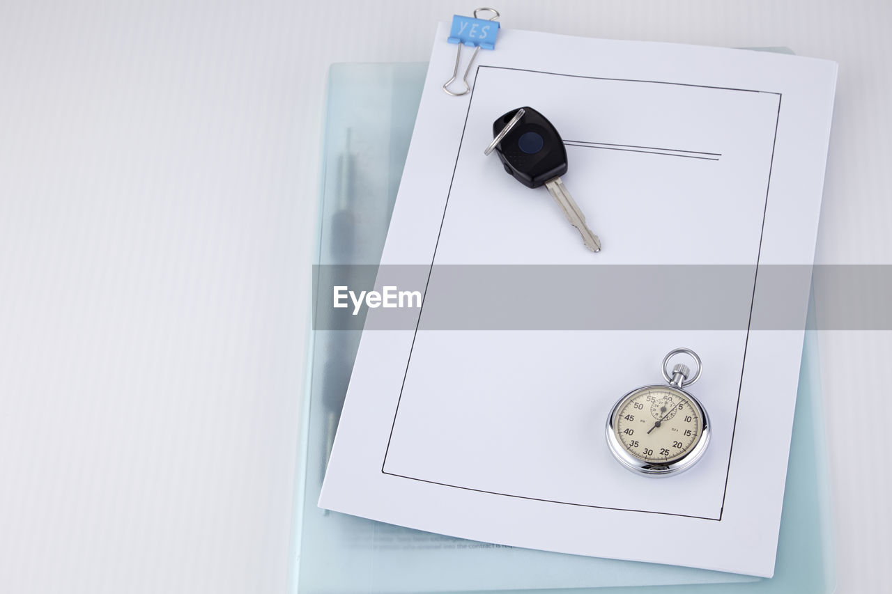 High angle view of car key and pocket watch on document