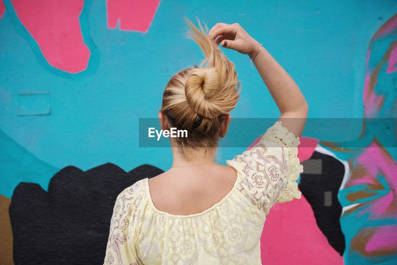 Rear view of woman with hair bun standing against wall
