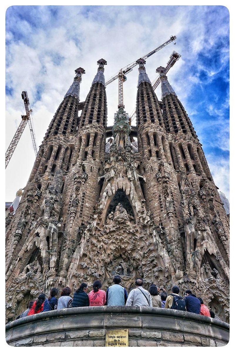 LOW ANGLE VIEW OF TOURISTS AGAINST CLOUDY SKY