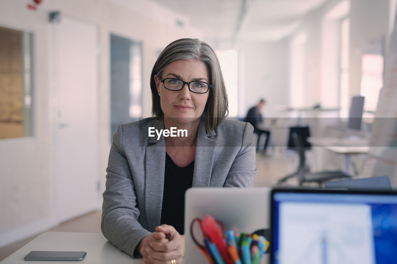 Portrait of confident mature businesswoman sitting at desk in office