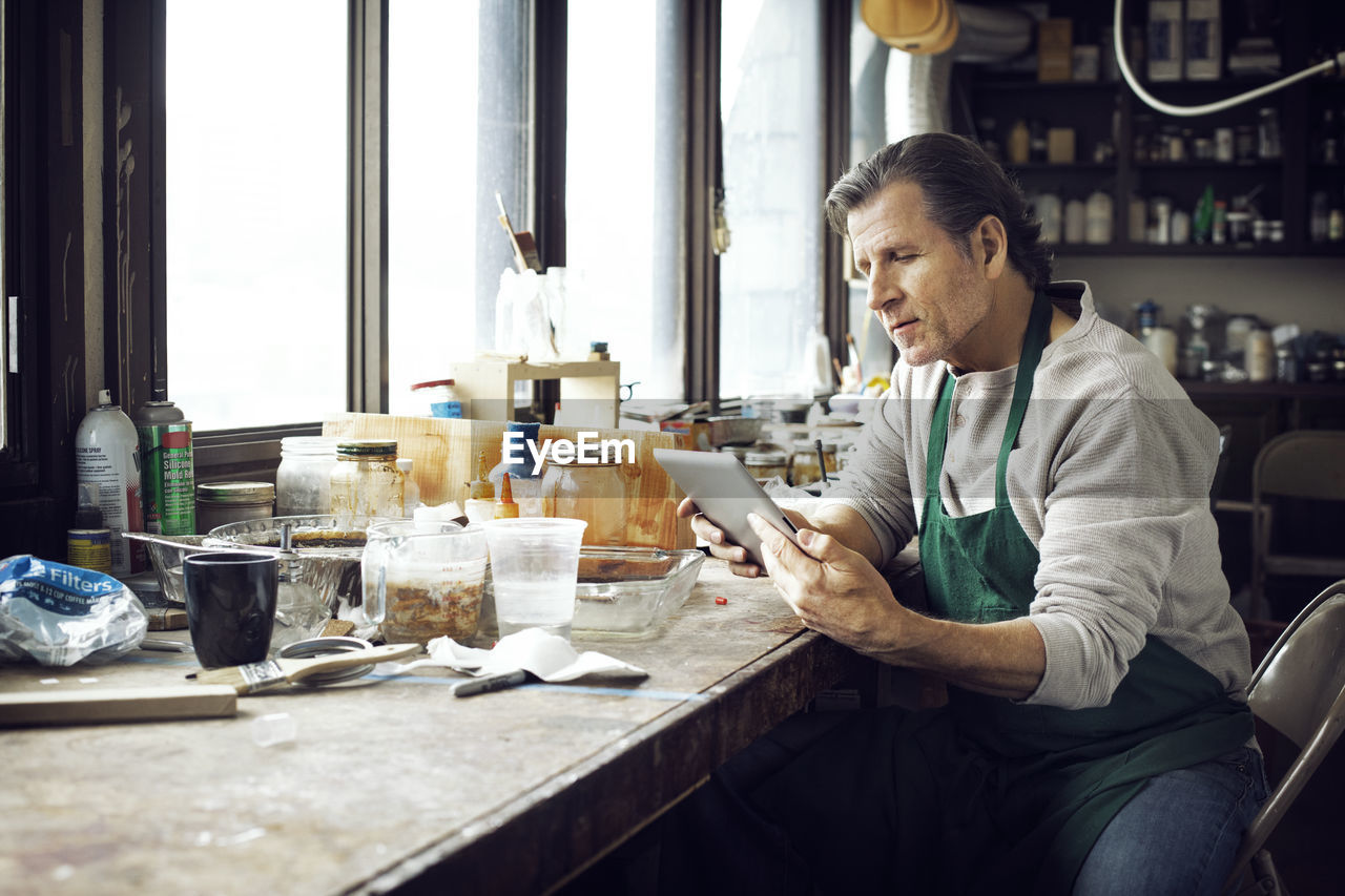 Man using tablet computer while sitting in workshop