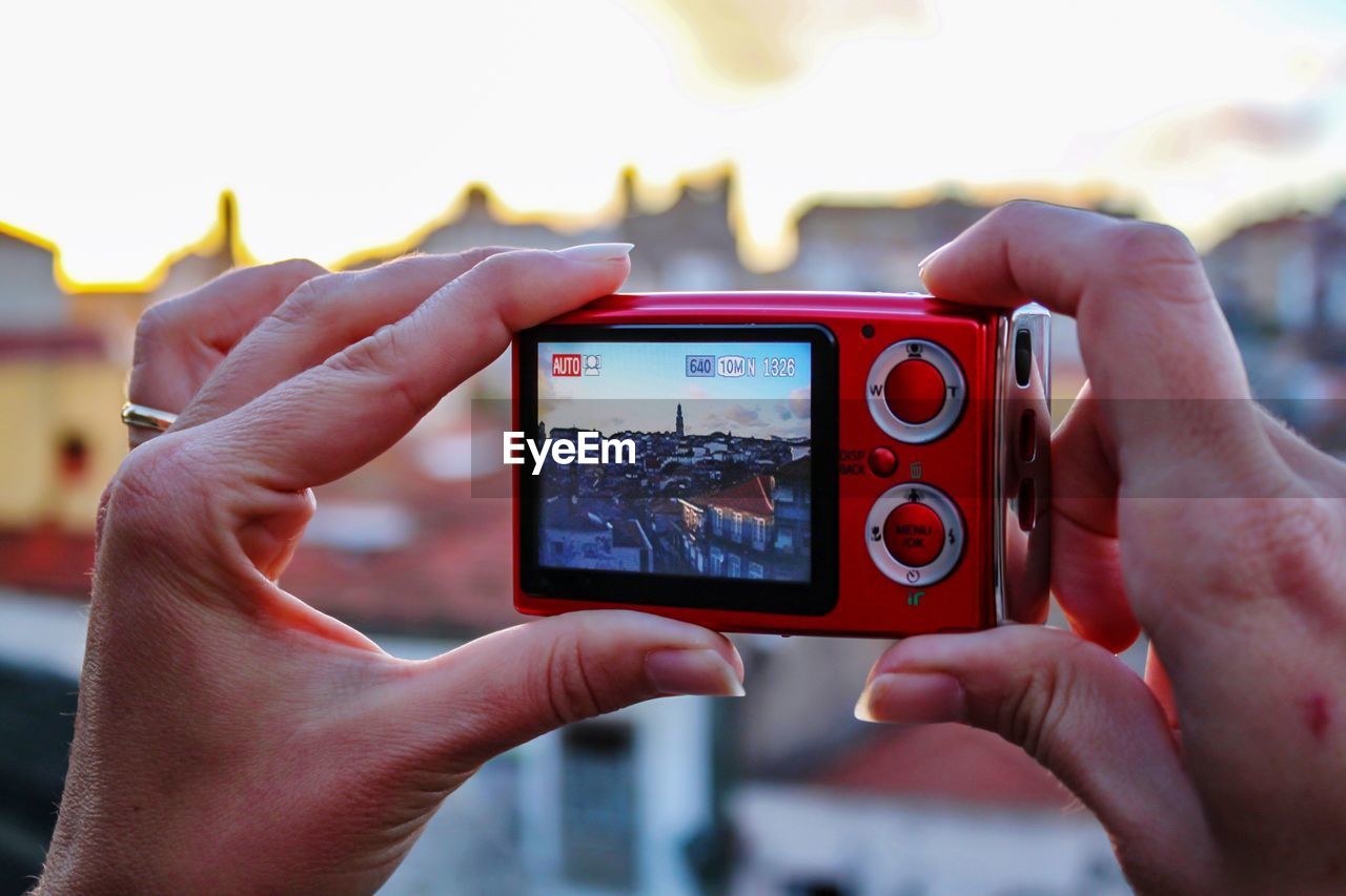 Cropped hands photographing town through camera