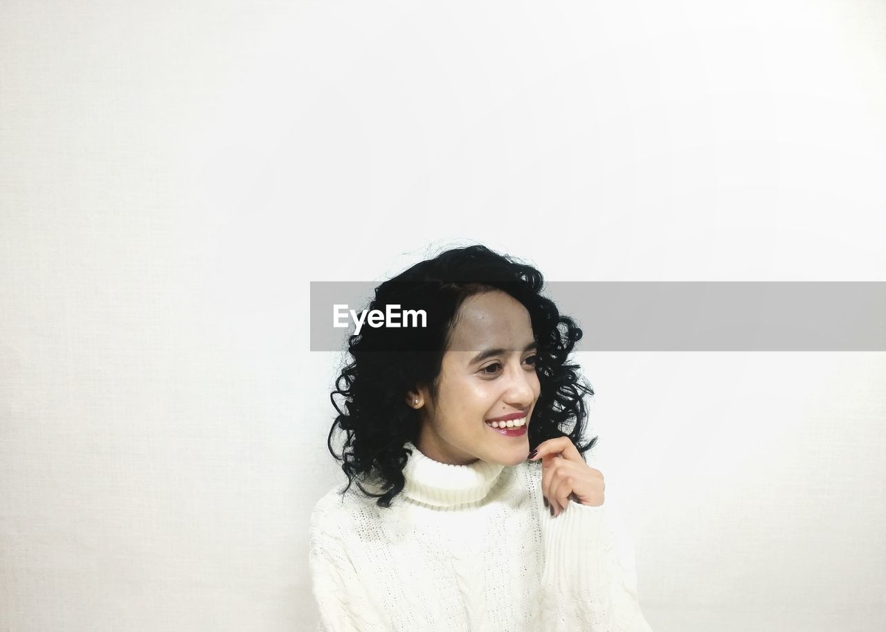 PORTRAIT OF YOUNG WOMAN WITH HANDS OVER WHITE BACKGROUND