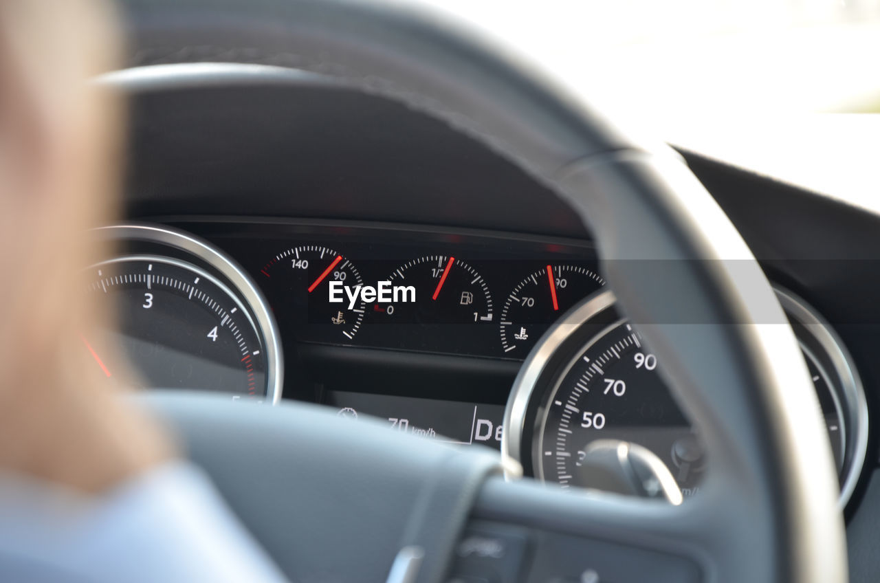 Closeup image of car dashboard through steering wheel during the day
