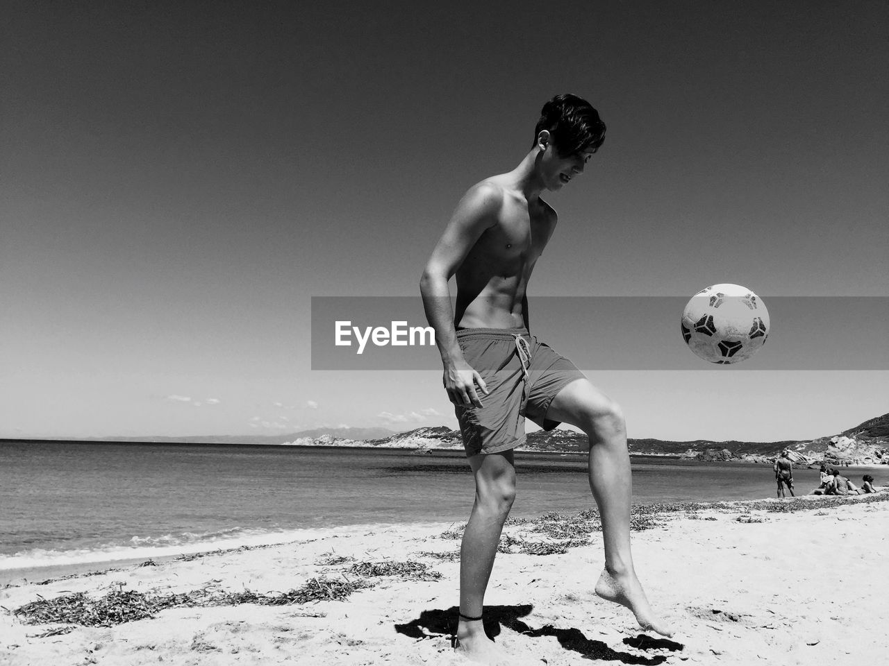 Man playing soccer at beach against sky