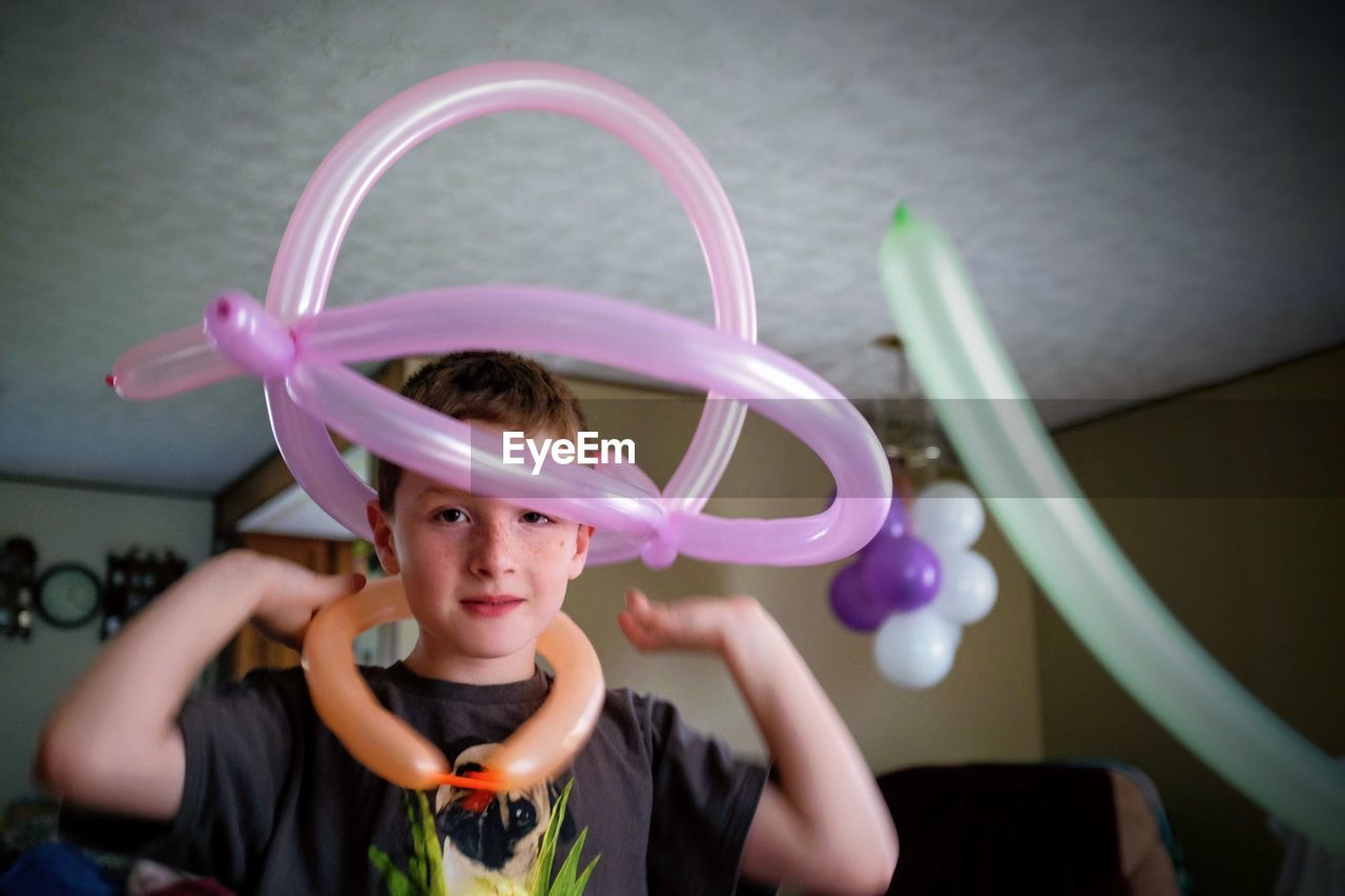 Portrait of boy holding balloons at home