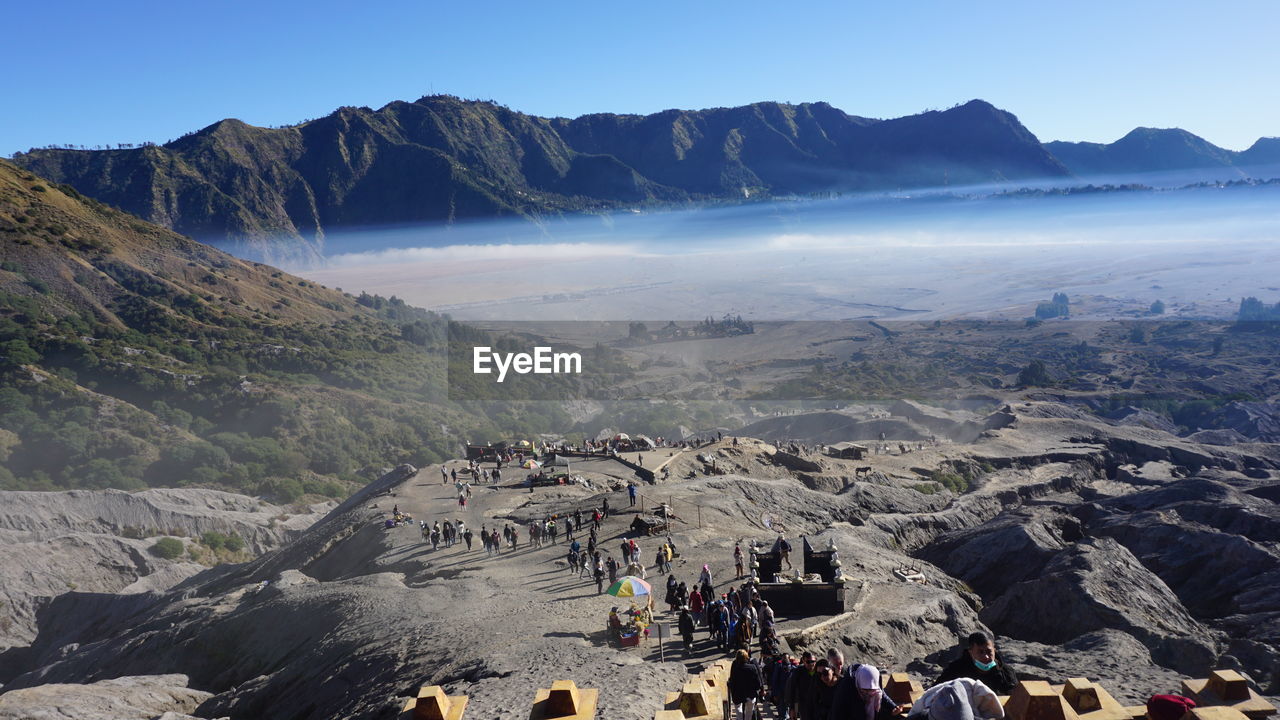 mountain, environment, landscape, mountain range, scenics - nature, nature, travel, leisure activity, sky, wilderness, travel destinations, beauty in nature, group of people, land, hiking, tourism, activity, adventure, valley, crowd, plateau, large group of people, outdoors, lifestyles, tourist, walking, day, non-urban scene, ridge, vacation, holiday, adult, trip, blue, rock, clear sky, men, high angle view, sunlight, backpacking, climbing, sunny, tranquility