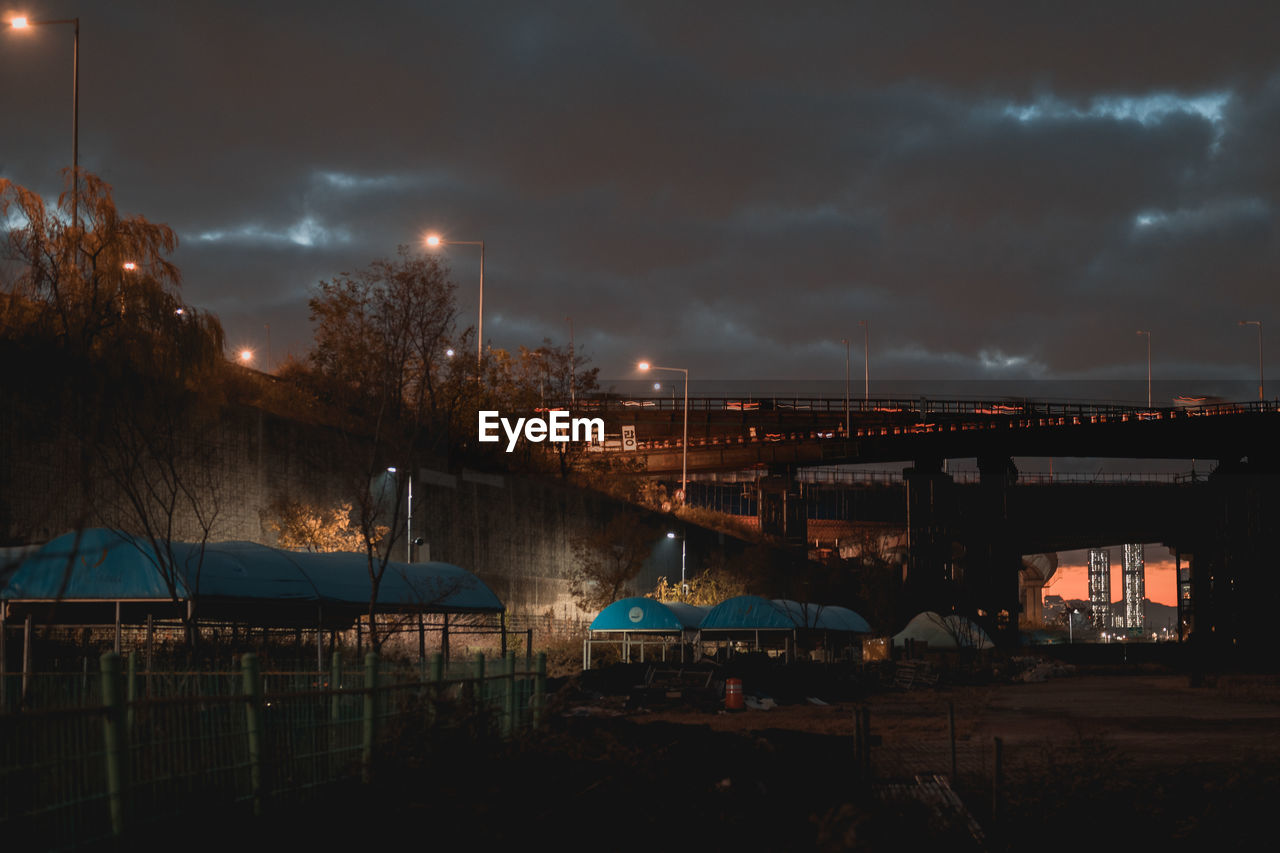 ILLUMINATED BRIDGE OVER WATER AT NIGHT