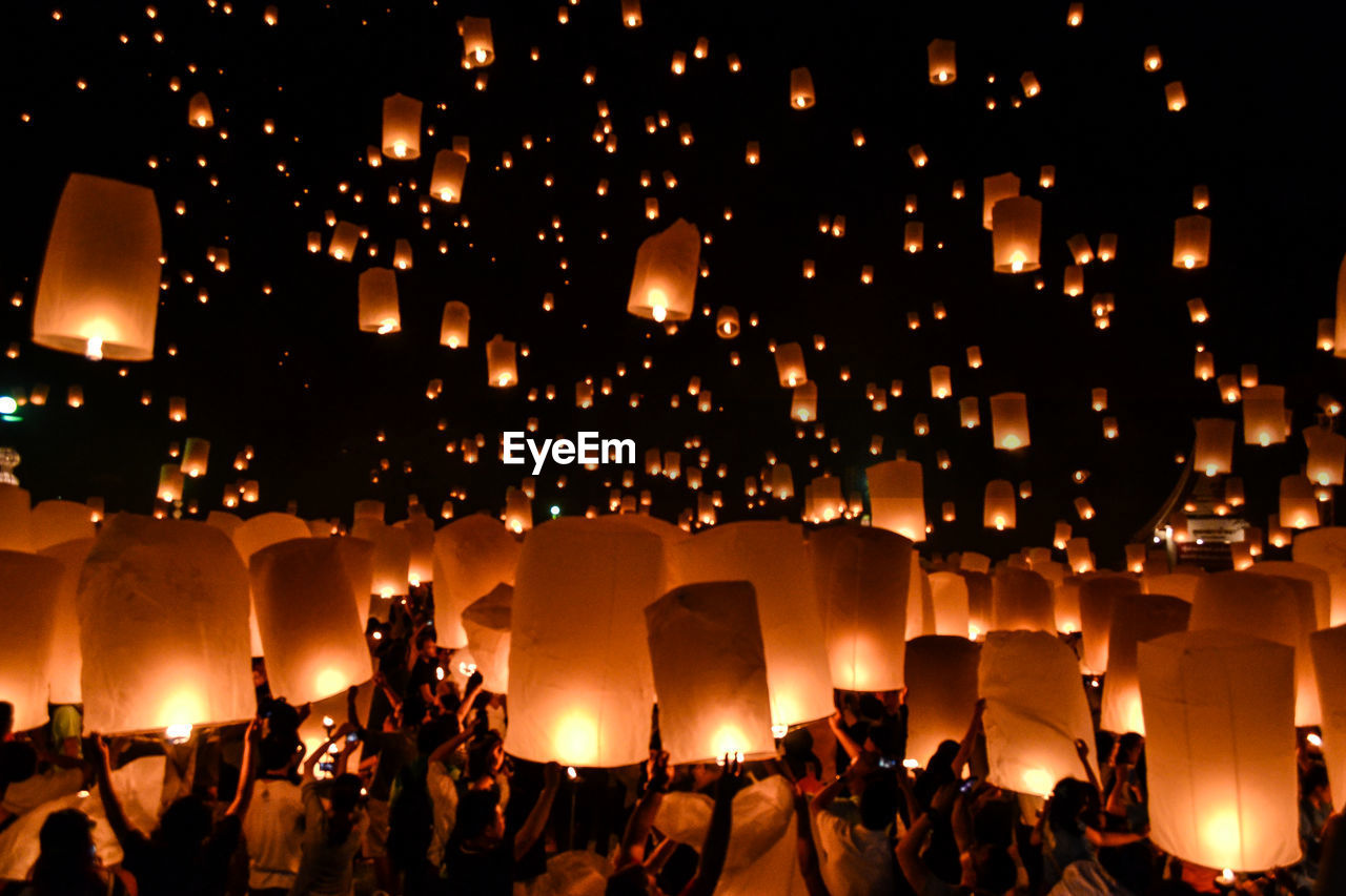 People holding paper lantern at night