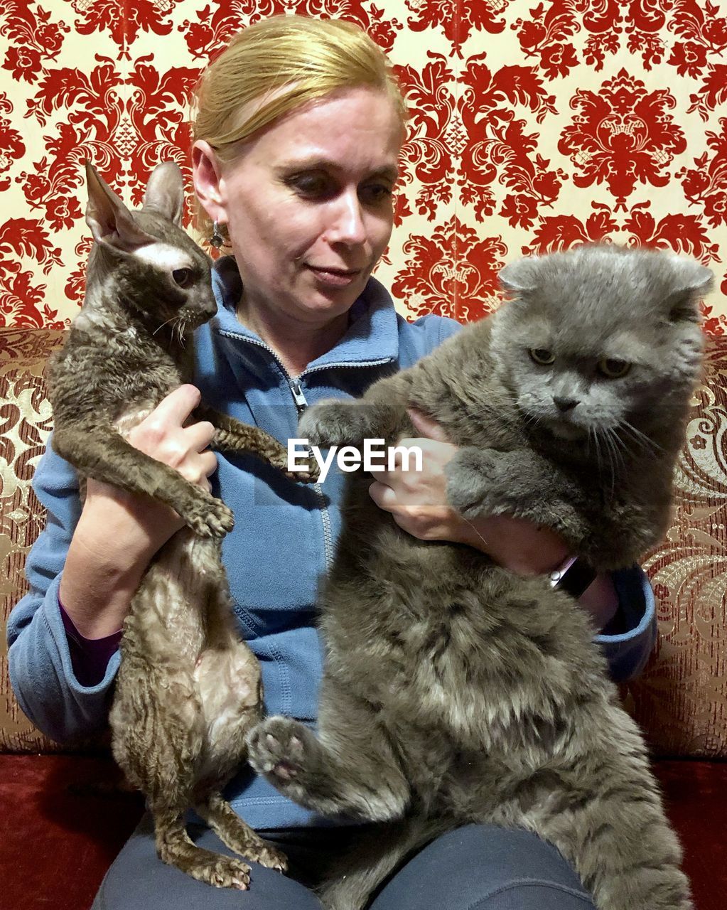 PORTRAIT OF YOUNG WOMAN WITH CAT SITTING ON WALL