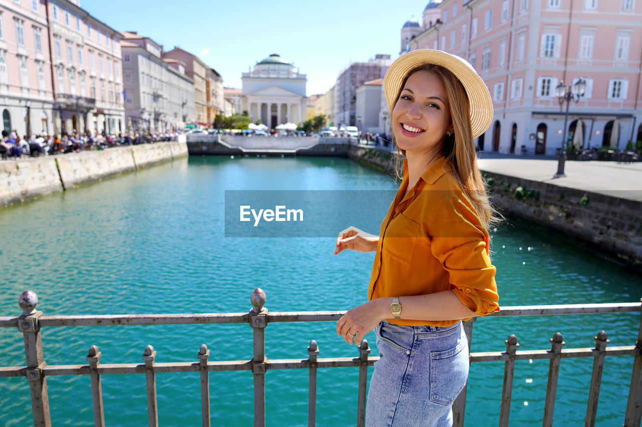 Traveler girl standing on the bridge with beautiful view of trieste city, italy