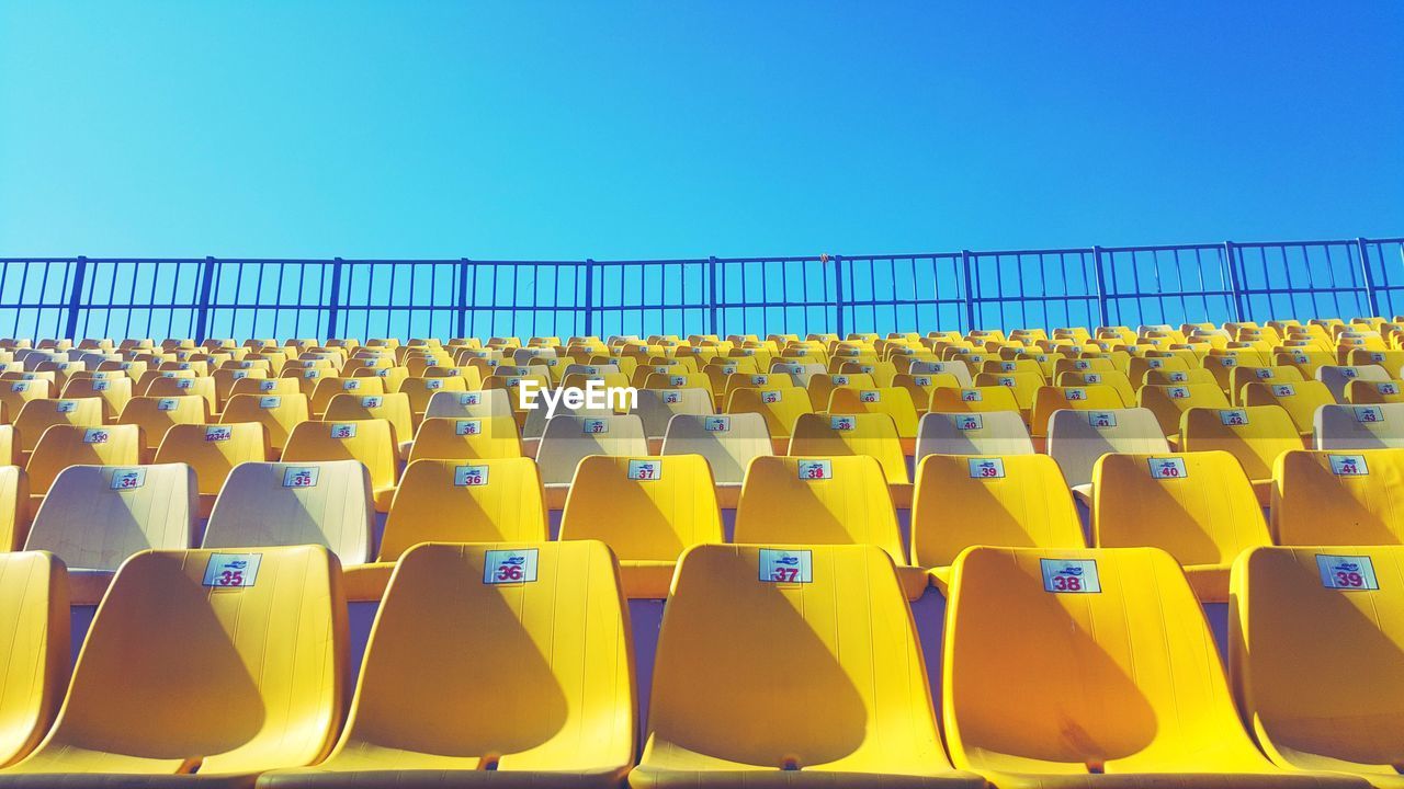 Empty chairs against clear blue sky