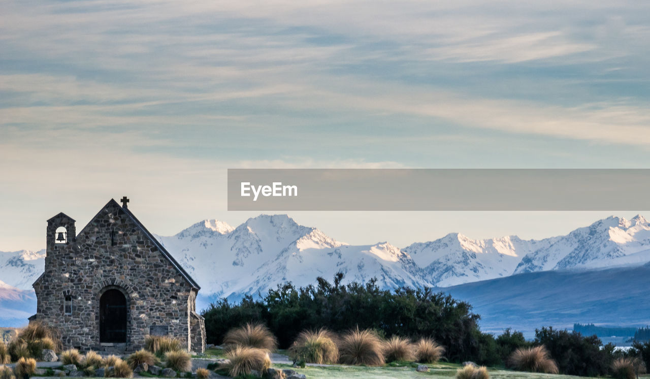 Small church with mountain backdrop shot during sunrise at lake tekapo, new zealand