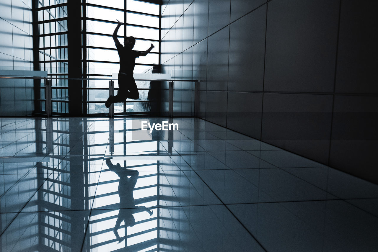 Silhouette boy jumping on tiled floor