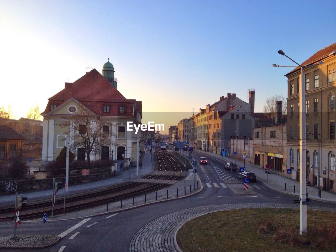 Street amidst houses against clear sky at sunset