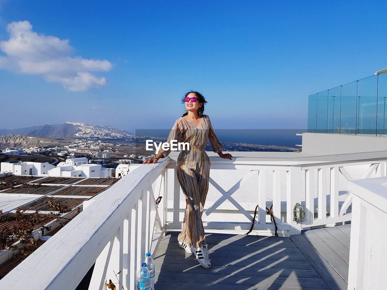 Woman standing by railing in city against sky