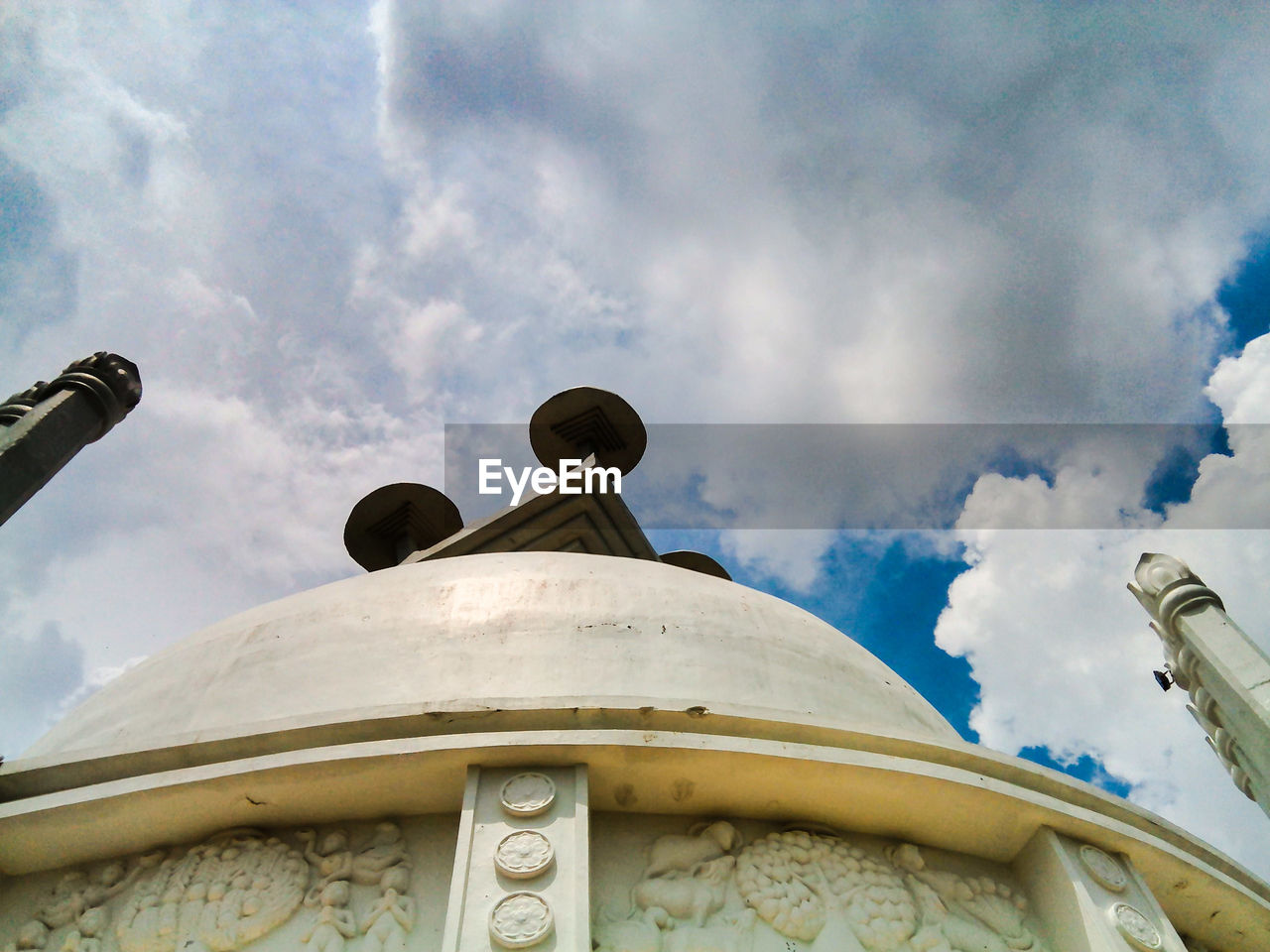 Low angle view of shanti stupa at dhauligiri against cloudy sky