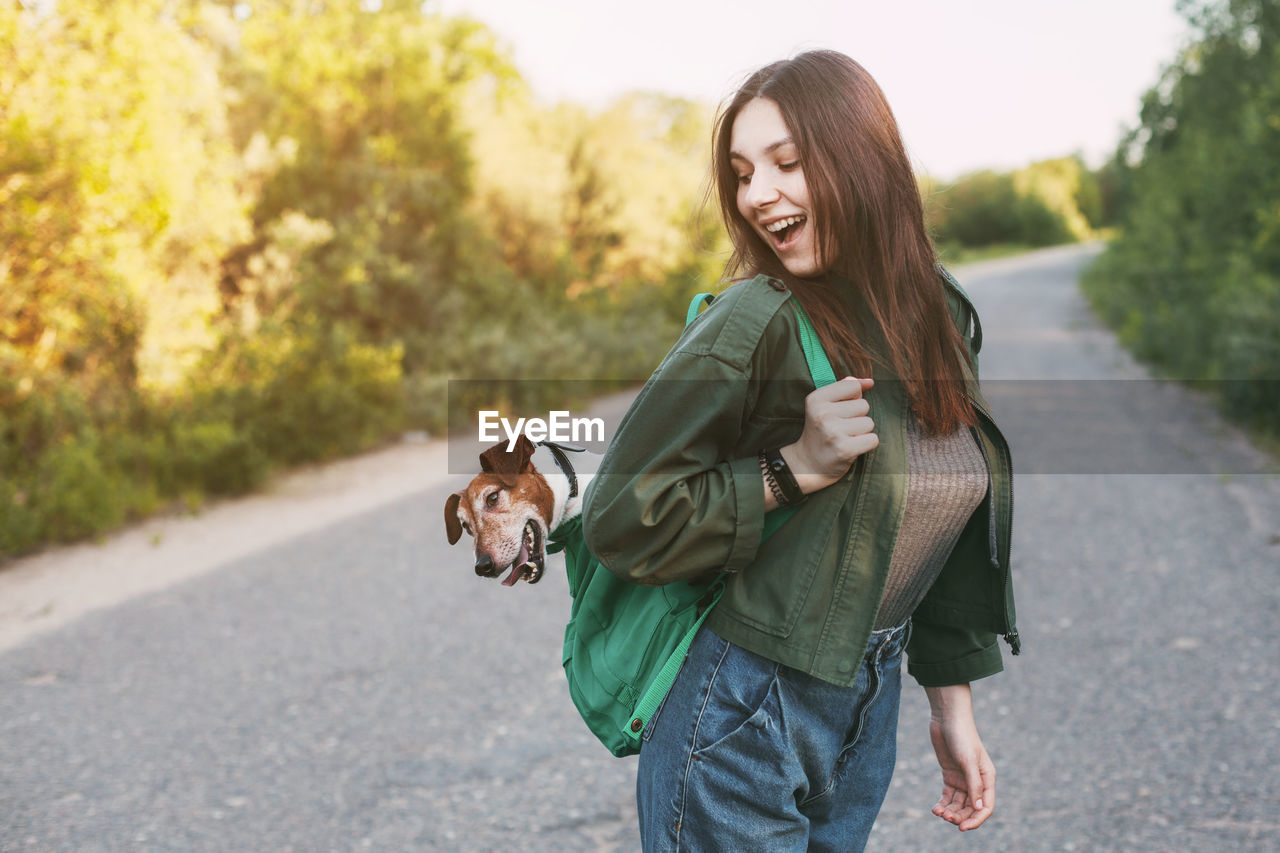 A beautiful girl is holding a green backpack on her shoulder, from which 