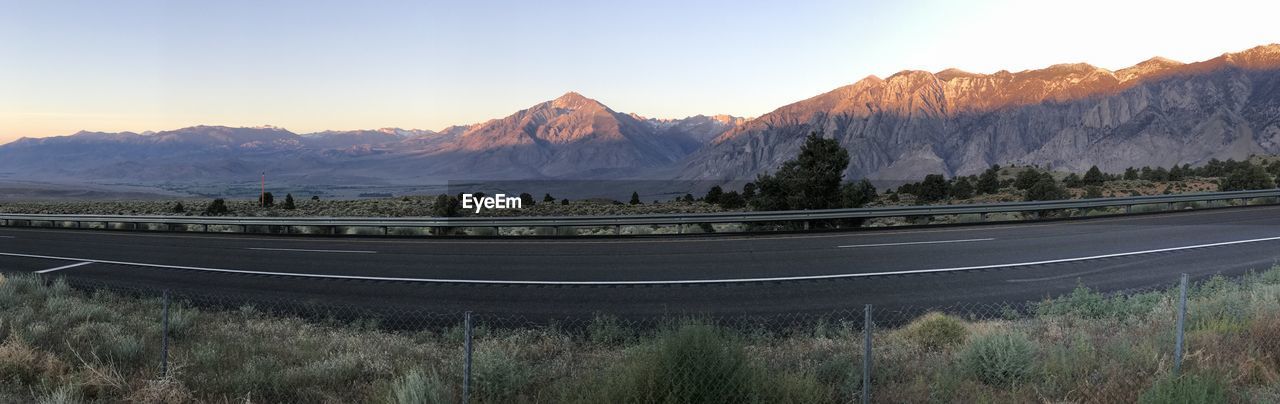 PANORAMIC SHOT OF ROAD BY MOUNTAINS AGAINST SKY