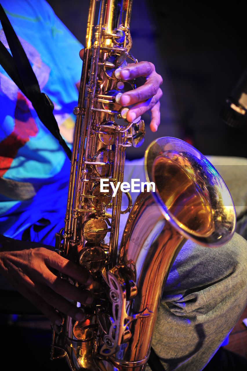 Midsection of mature man playing saxophone